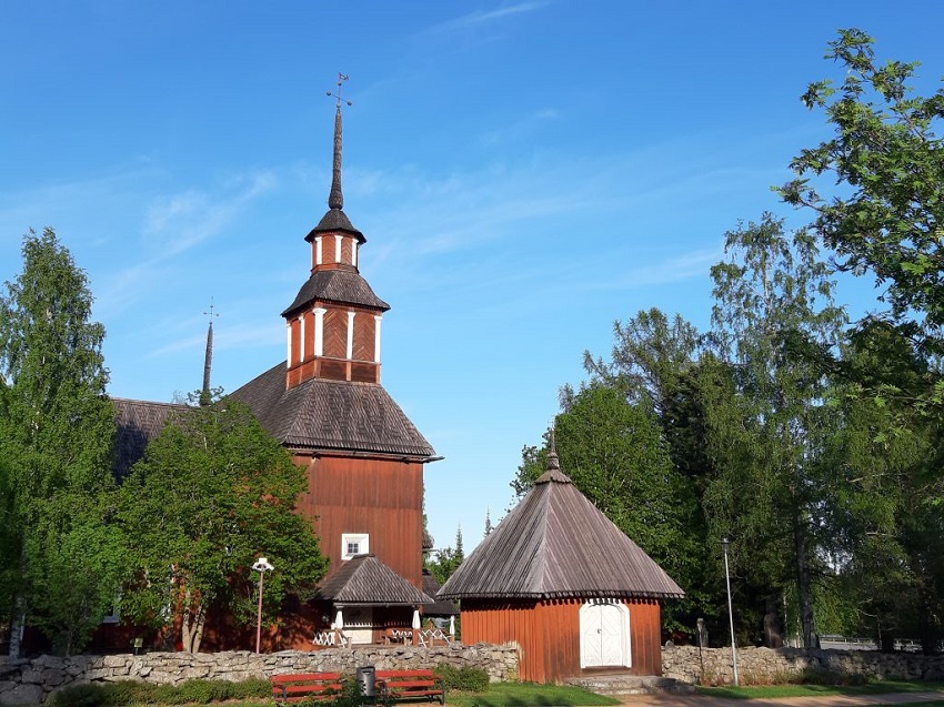 Punainen keskiaikainen puukirkko kesällä. Kuvassa myös pieni tapuli