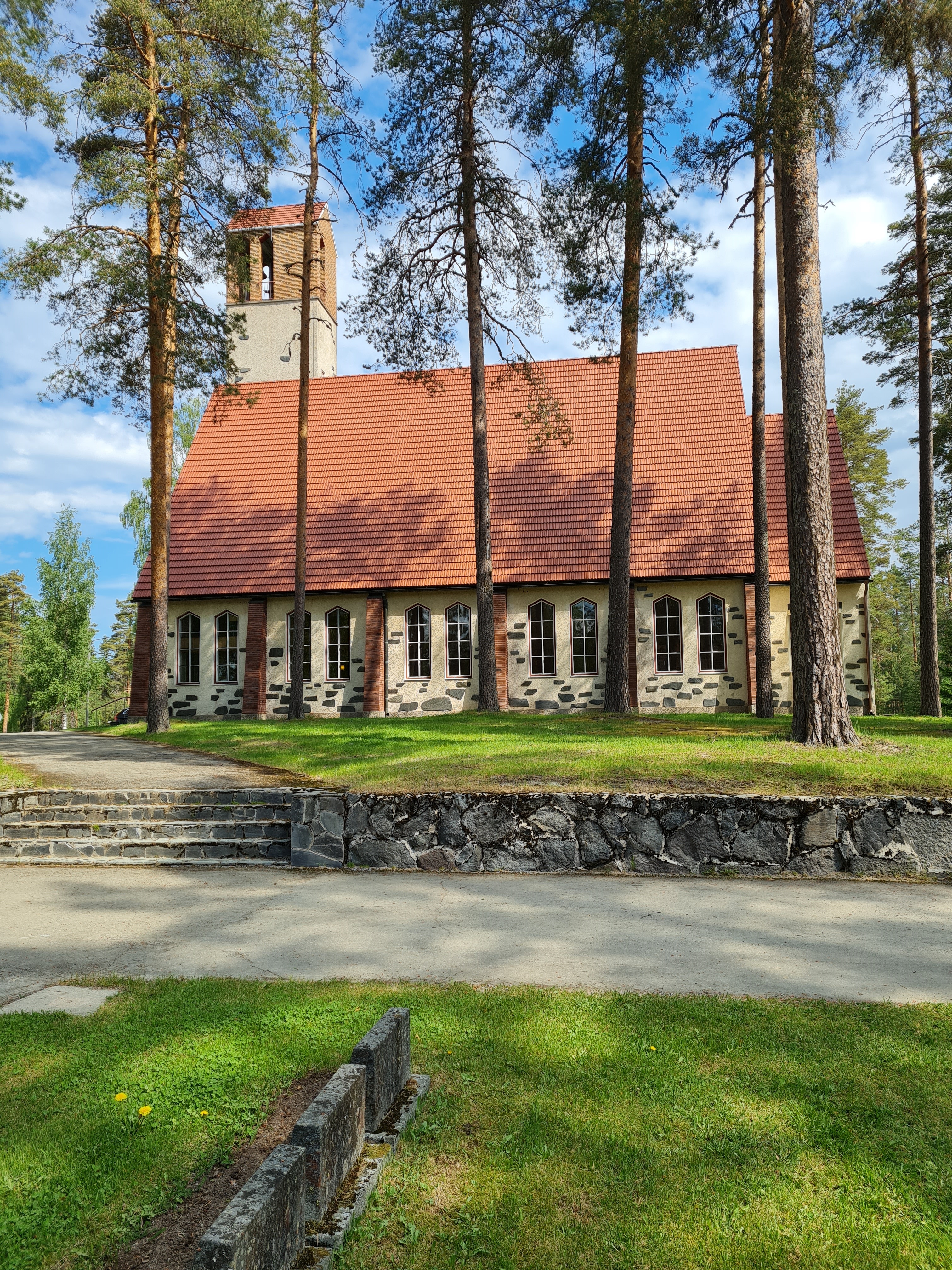 Vaalea kivikirkko, jossa  on jyrkkä katto ja kellotorni. Lunta on maassa.